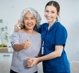 woman caregiver and elder woman doing thumbs up