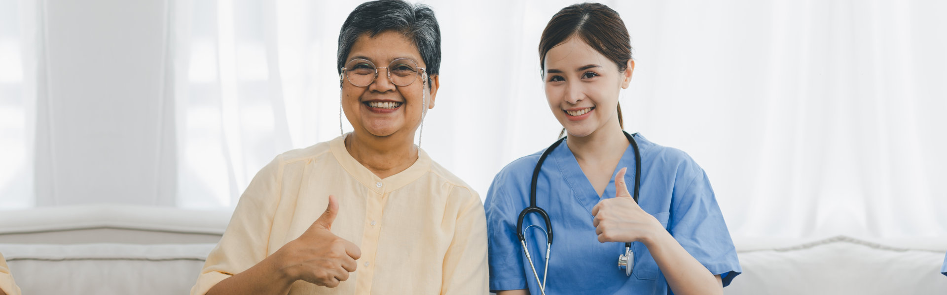 caregiver and elder woman doing thumbs up